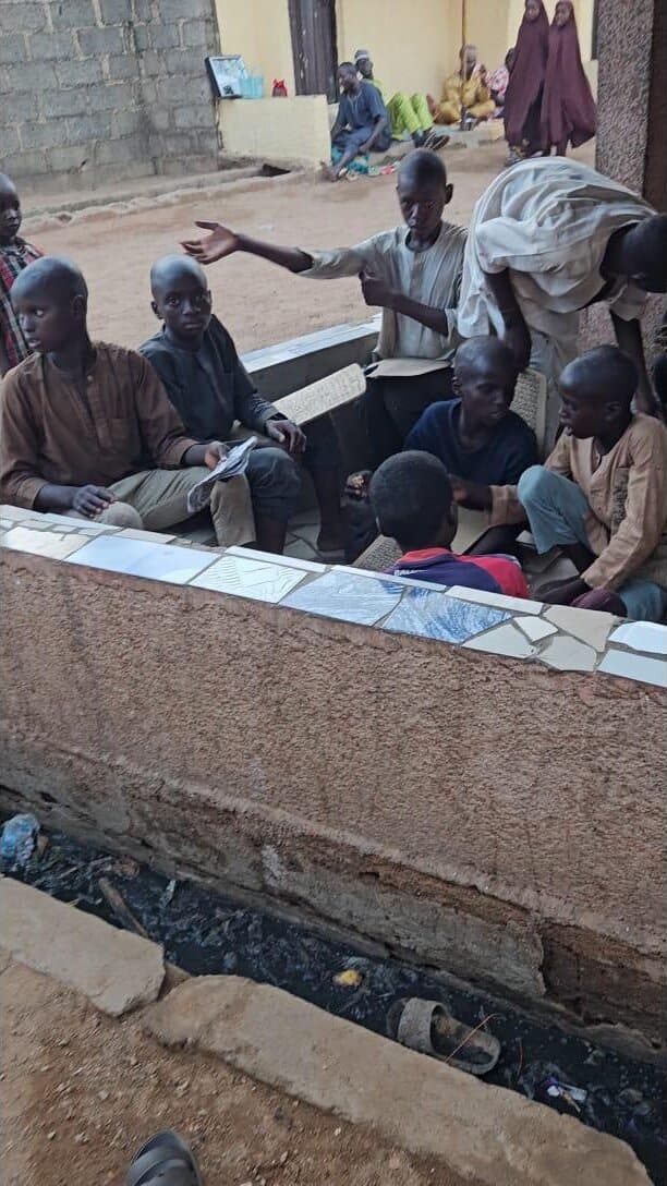 A community elder with children gathered at an outdoor school supported by the foundation