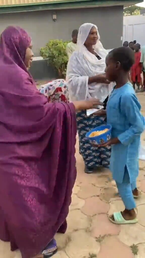Two volunteers welcome a boy at a food distribution in a Kaduna compound