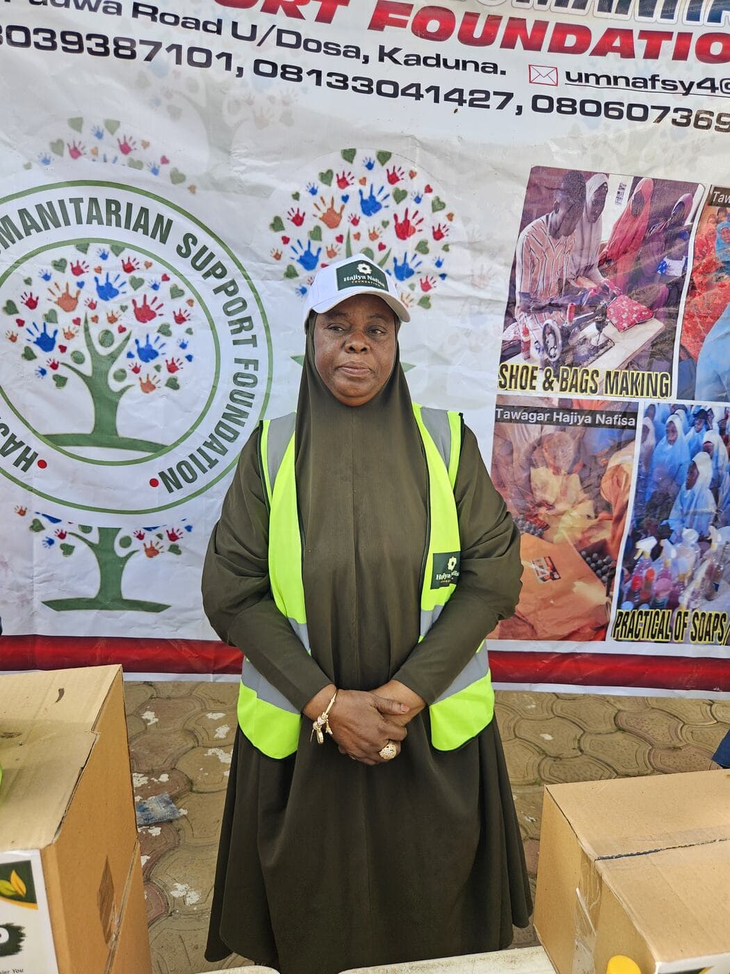 Hajiya Nafisa Umar in a volunteer vest in front of the foundation banner in Kaduna