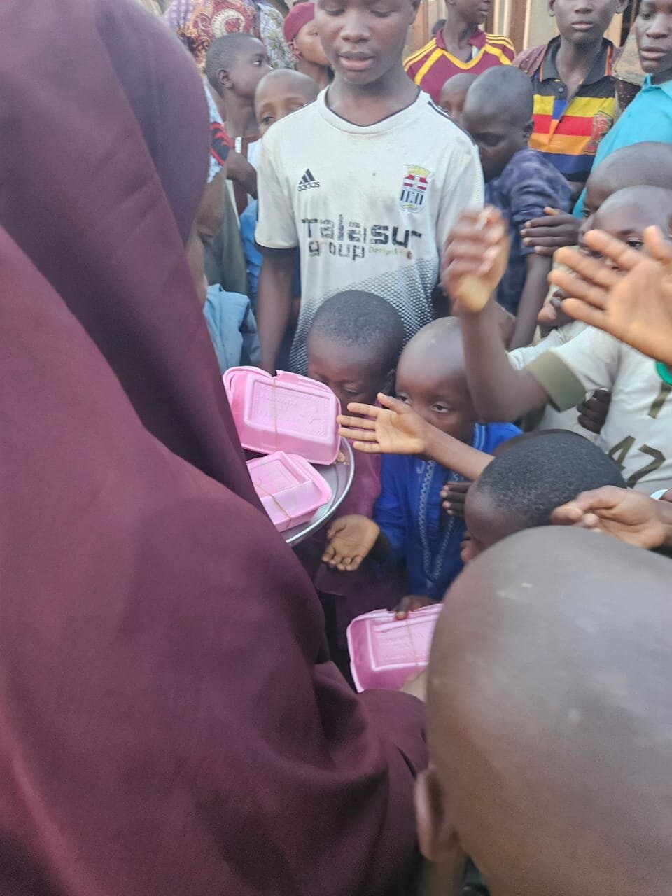 Trays of packed meals being handed out to a crowd of children